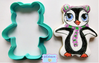 The cookie cutter flips show a teddy bear cutter turned into a winter penguin with earmuffs and a scarf. The image depicts the teddy bear cutter turned into a winter penguin with a scarf and earmuffs.