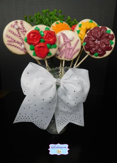 Display of cookies on a stick made into a flower bouquet with sugar cookies and royal icing.