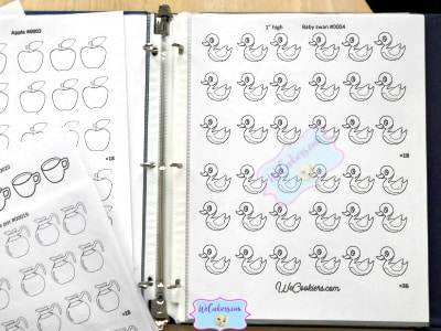Royal icing transfer sheets in alphabetical order in a notebook. This shows a baby swan template.
