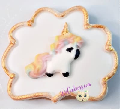 This sweet little unicorn is a royal icing transfer from WeCookier's transfer collection. These make for a fast and easy method of decorating, yet still looks professional. Image of a unicorn royal icing transfer placed on plain white sugar cookie icing with a border.
