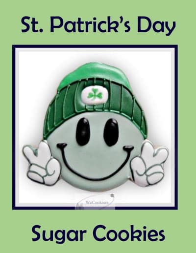 Green St. Patrick's Day smiley face cookie wearing a skull cap and making peace signs with both hands