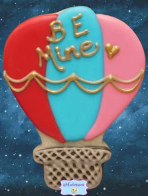 A hot air balloon cutter turned into a Valentine's day 'Be Mine' cookie V-day hot air balloon decorated sugar cookie with royal icing