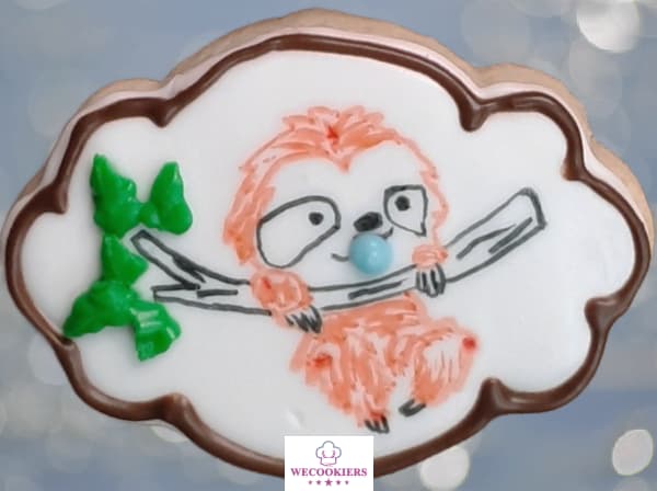 Using food color markers to decorate sugar cookies can save so much time. You could also paint it on instead. Piping a pacifier in its mouth adds a 3D look. This cute baby sloth was simply drawn on using a food color marker with a border around the cookie. I piped a blue pacifier in its mouth for depth.