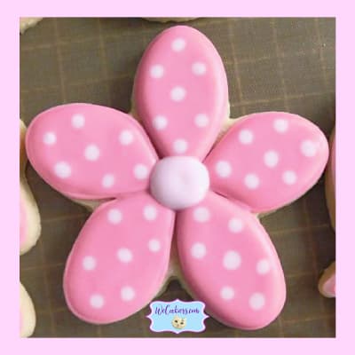 A flower cookie was done for a girl's baby shower cookie. Flooded in pink, it has white dots that were made using the wet-on-wet technique. A sweet flower baby girl shower cookies. It shows the wet-on-wet-technique. See more inspo, popular cutters, techniques, and RI transfer sheets here: