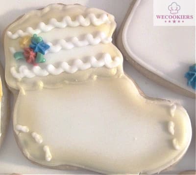 A baby bootie flooded in white with gold airbrushing around the perimeter. A couple of starlets in burgundy and navy blue accents this sweet cookie. Adding airbrushing to baby girl shower cookies is a great way to take them to a professional level and make them the star of the show! See more ideas, techniques, popular cutters & RI transfer sheets: