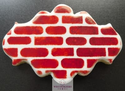 This is a cookie decorated with the spouncing method with sponges and a cookie stencil. It shows a brick wall