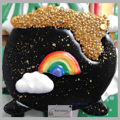 The photo shows a pot of gold decorated sugar cookie with 2 royal icing transfers of a rainbow and a cloud. You can get the transfers in Shop Gotta-havs! by WeCookiers.com