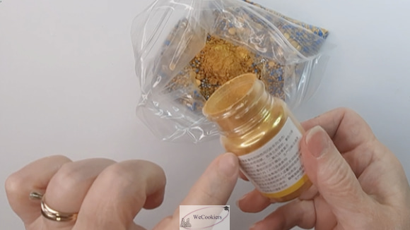 This photo shows a bag of different colored sprinkles with gold lustre dust being poured into it.