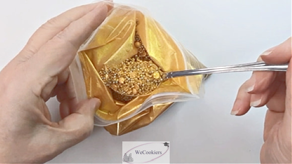 This photo shows an open bag of golden sprinkles being spooned out.